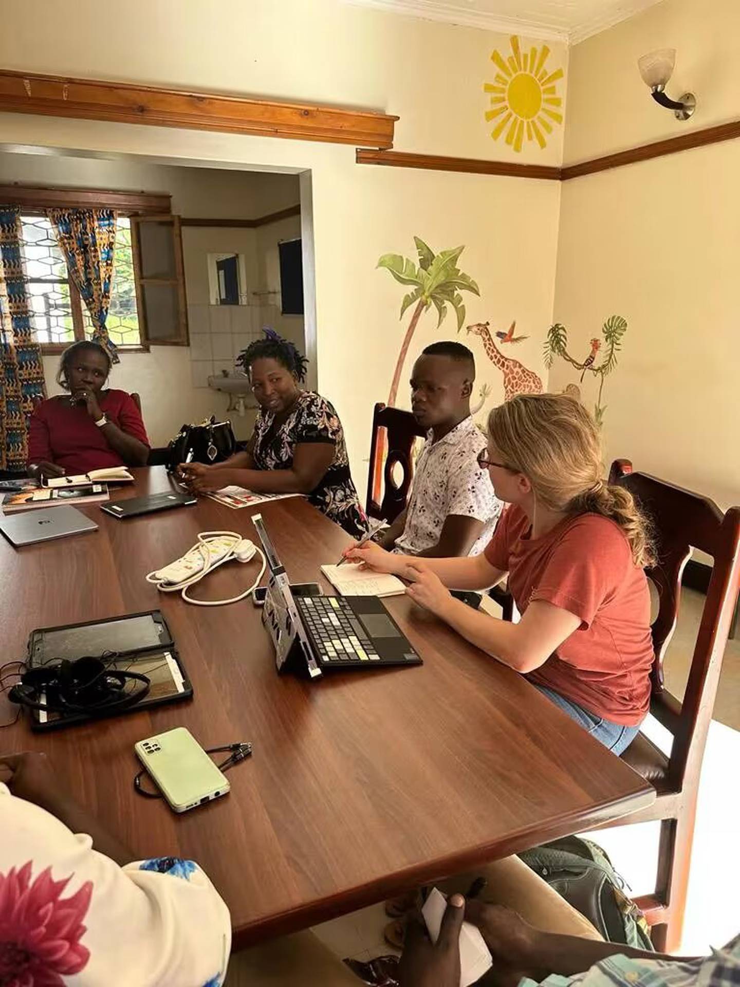 Kelsey Brown, a la derecha, trabaja con el equipo ugandés de enfermeras y gestores de casos que utilizarán el dispositivo de IA para detectar cardiopatías reumáticas en Lira (Uganda) (Hospital Nacional Infantil)