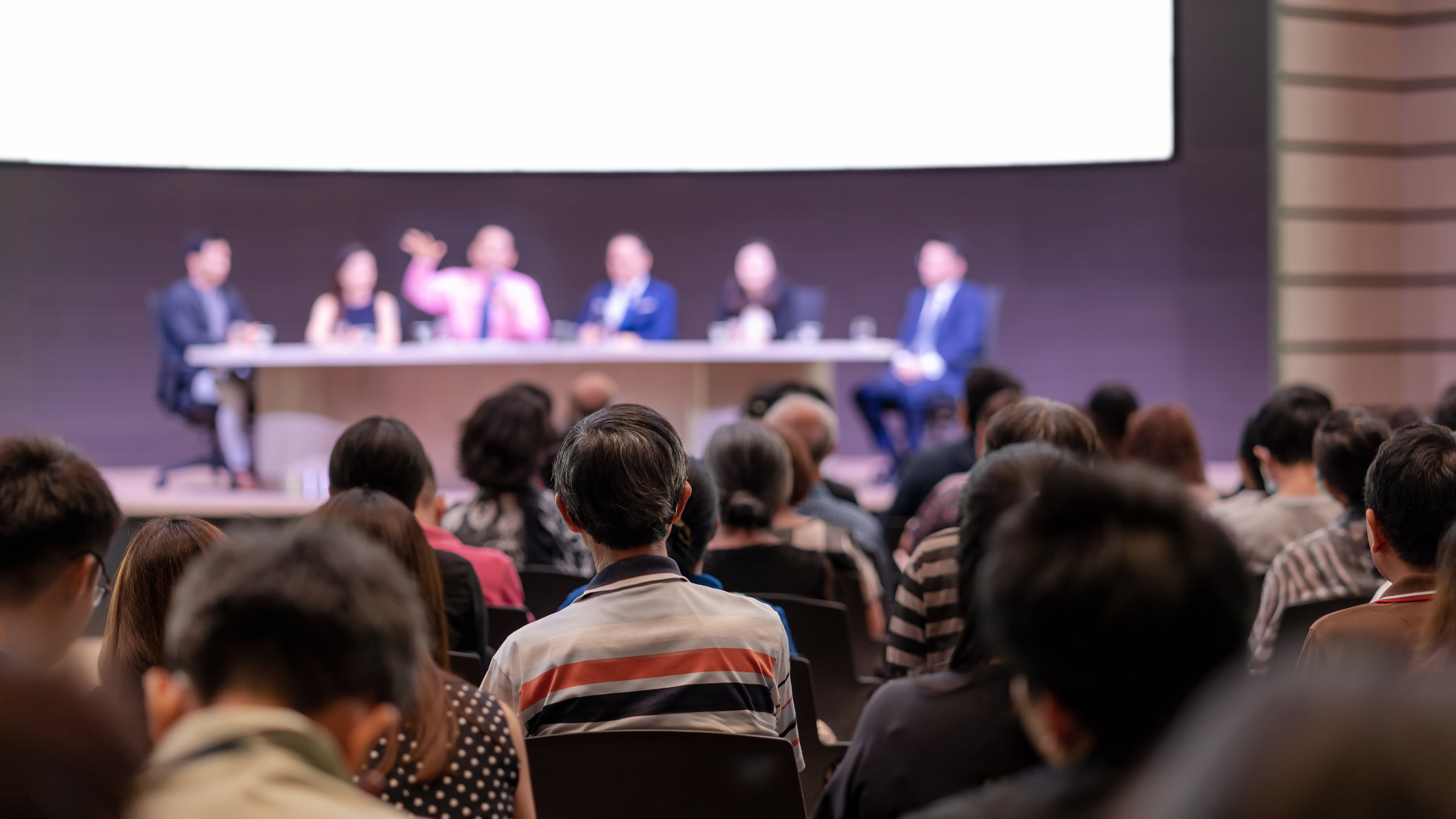 Vista de la audiencia en la sala de conferencias o reunión de seminario donde los oradores están intercambiando ideas y hablando en el escenario, negocios y educación sobre el concepto de inversión.