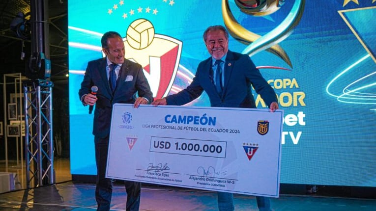 Francisco Egas entrega un cheque de Conmebol a Isaac Álvarez