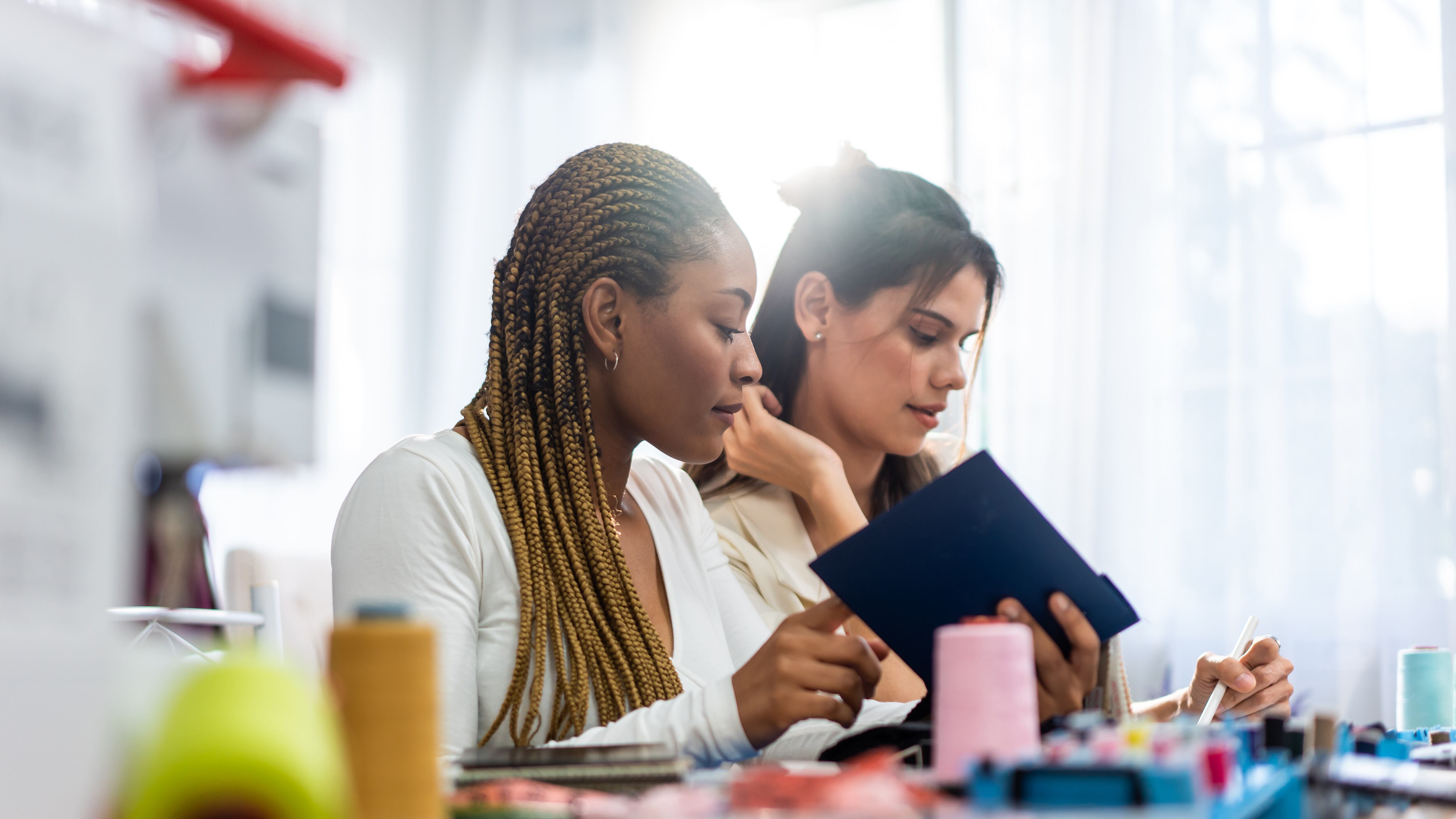 Diversas diseñadoras de moda para mujeres trabajan diseñando ropa en un taller de sastrería.