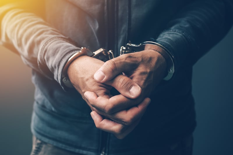 Delincuente arrestado con esposas, primer plano de las manos.