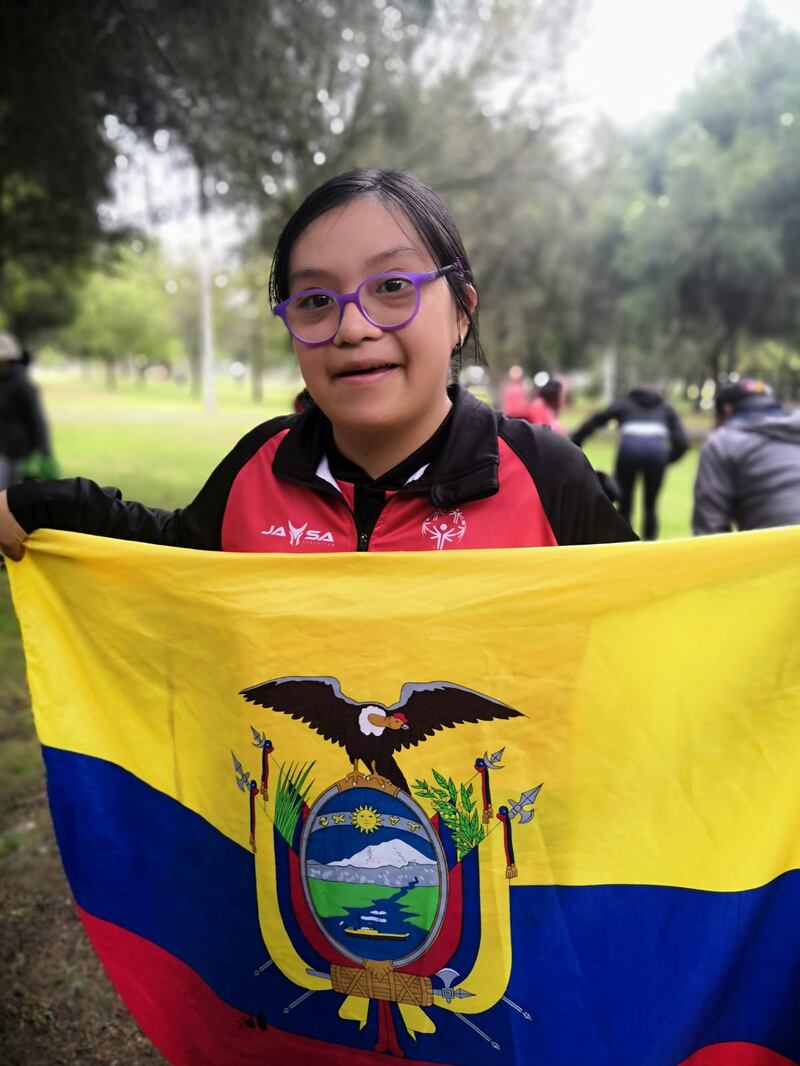 Una niña deportista de Olimpiadas Especiales levanta la bandera de nuestro país con satisfacción y alegría.