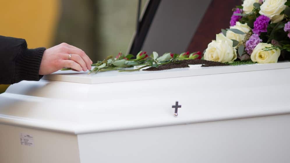 Primer plano de la mano de una persona en un ataúd con un fondo borroso