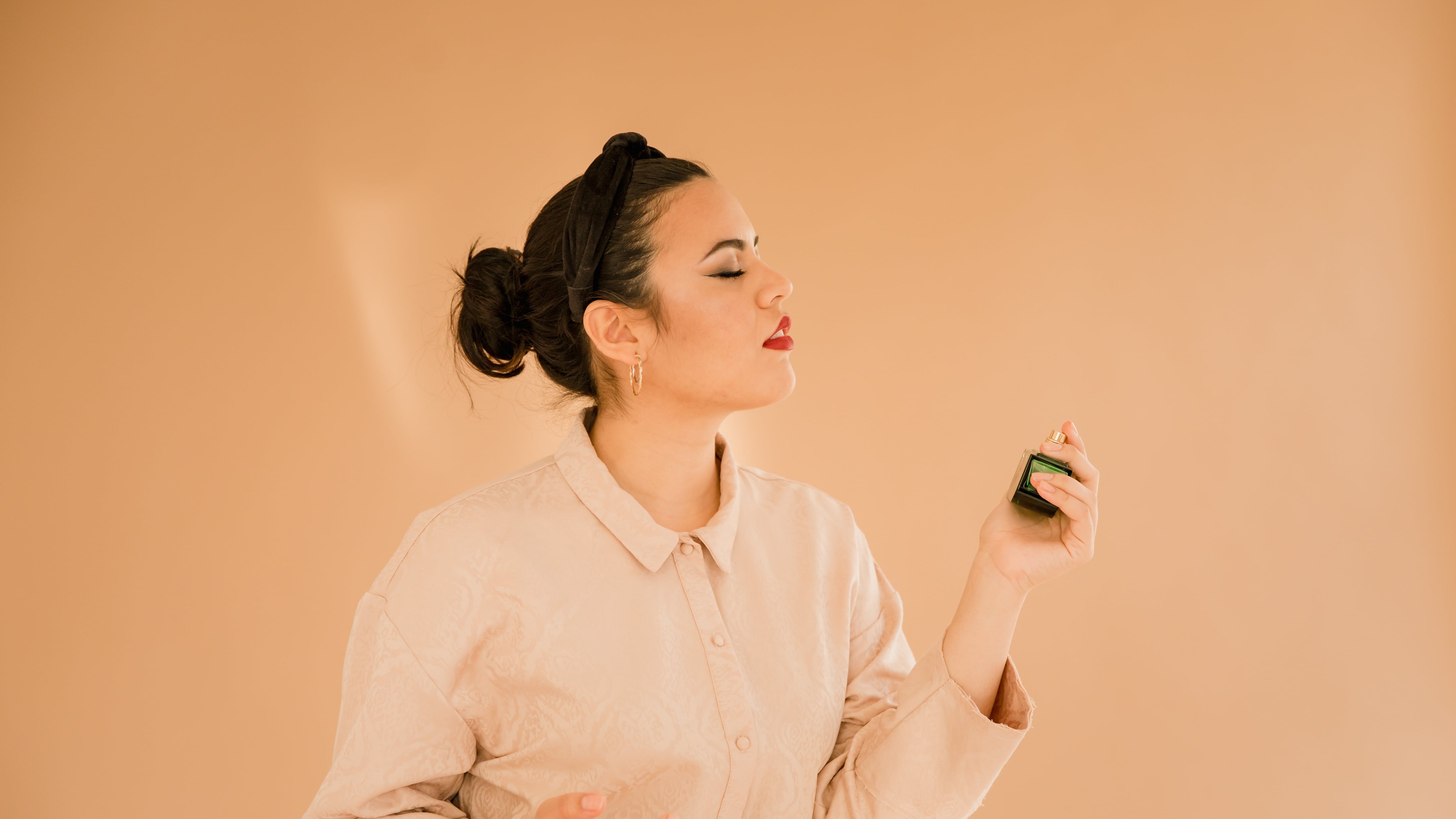 Mulher borrifando frasco de perfume