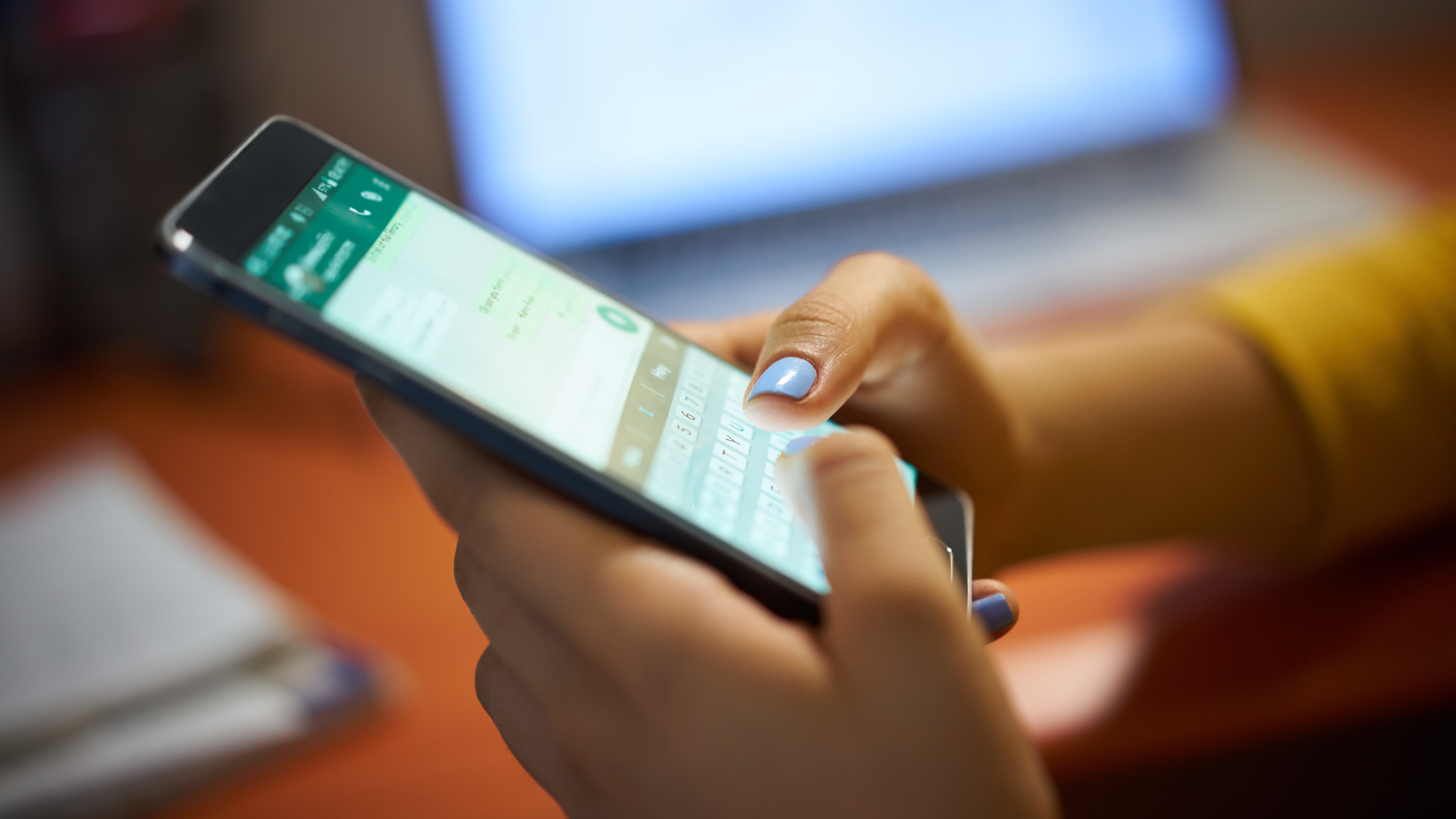 Mujer joven que usa un teléfono celular para enviar mensajes de texto por WhatsApp