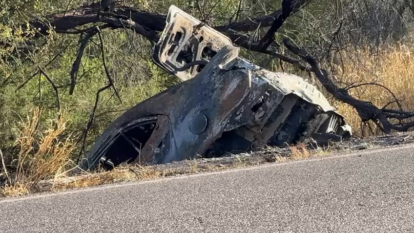 mujer atada junto a un auto en llamas