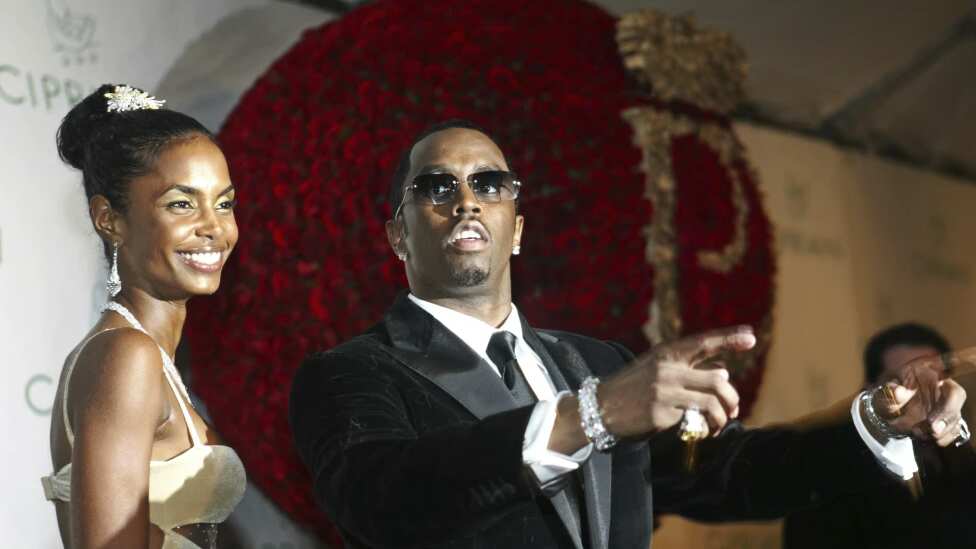 Sean “P. Diddy” Combs dirige a los fotógrafos mientras le cantan “Feliz cumpleaños”, mientras Kim Porter, a la izquierda, escucha