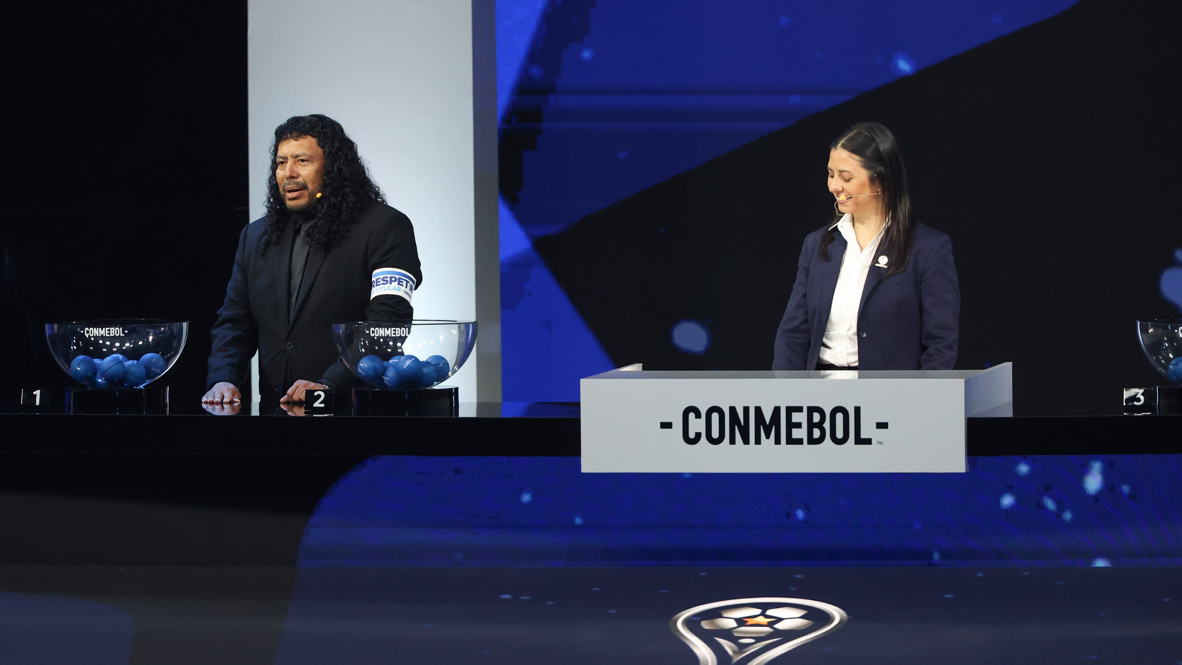 AMDEP2298. LUQUE (PARAGUAY), 19/03/2026.- La gerenta de Competiciones de Conmebol, Luciana Antunes (d), y el exfutbolista René Higuita hablan durante el sorteo de la fase de grupos de la Copa Sudamericana 2026 este jueves, en Luque (Paraguay). EFE/ Juan Pablo Pino