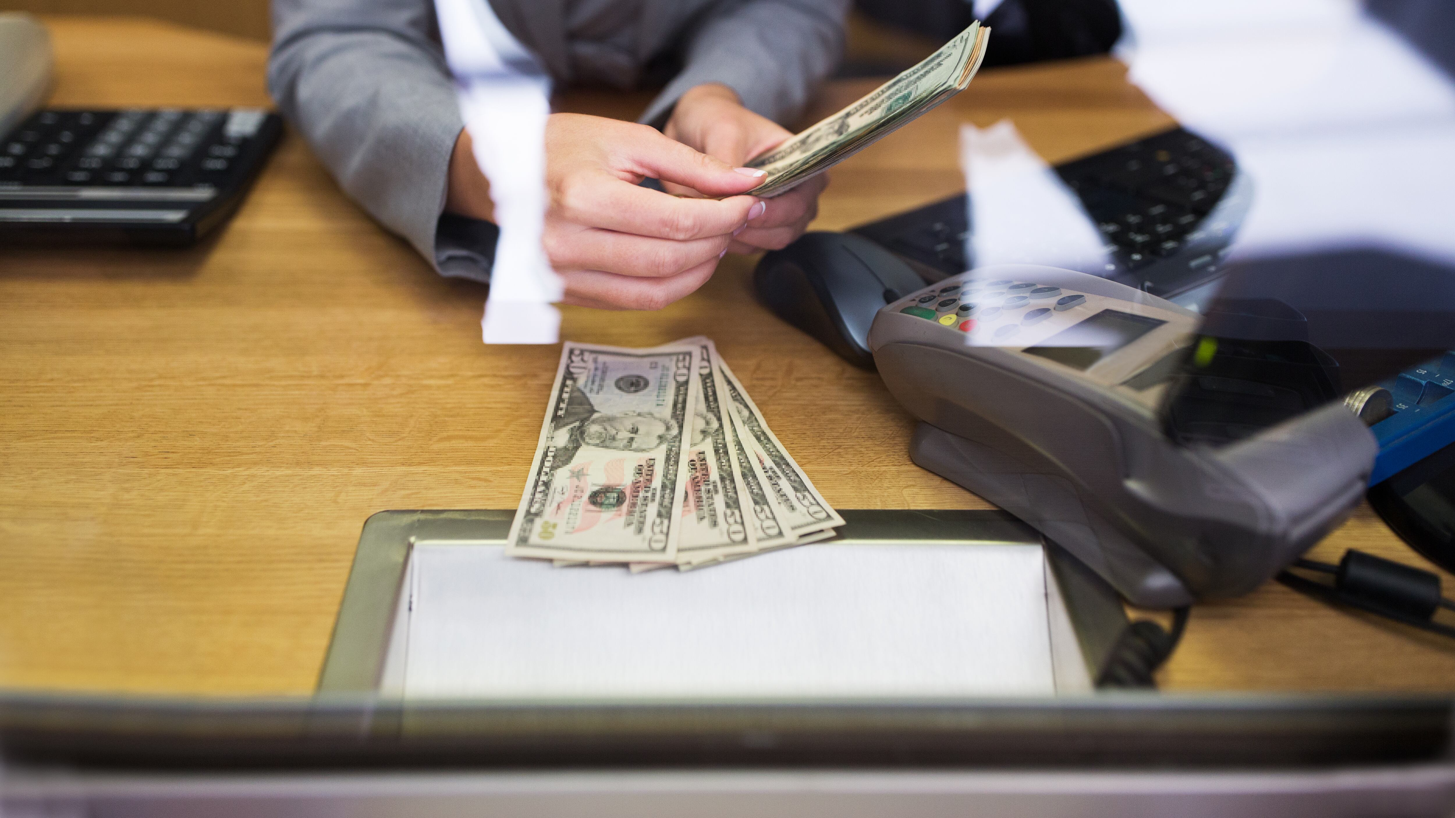 Empleado que da dinero en efectivo al cliente en la oficina del banco o en el cambiador de divisas