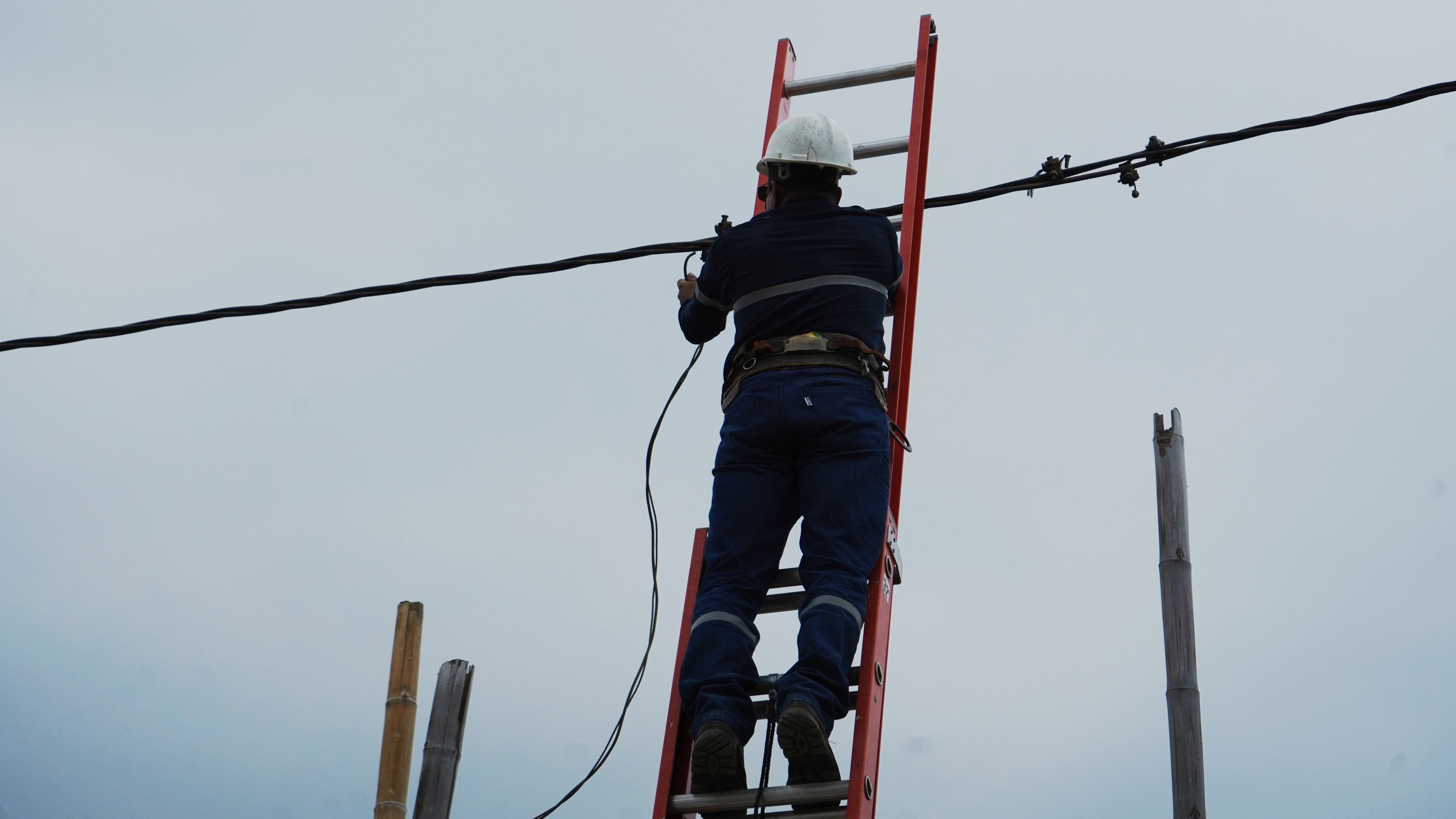 En la gráfica, un empleado de CNEL durante un trabajo de mantenimiento y cambio de cable
