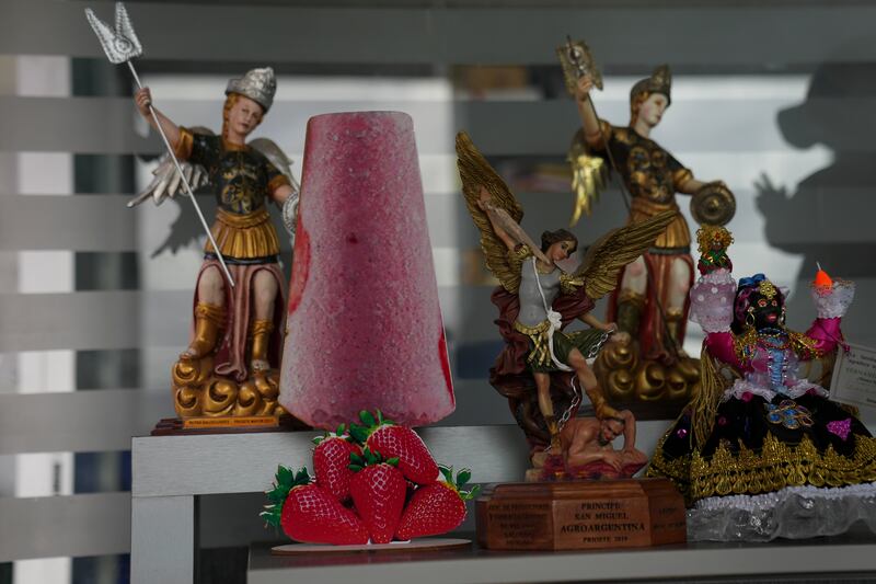 Una silueta de paleta en cartón adorna un estante junto a una figura del arcángel san Miguel, patrón de Salcedo, en Ecuador, el jueves 28 de noviembre de 2024, durante una sucesión de apagones provocados por una prolongada sequía. (AP Foto/Dolores Ochoa)