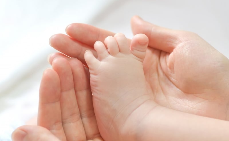 Pies del bebé en manos de la madre.