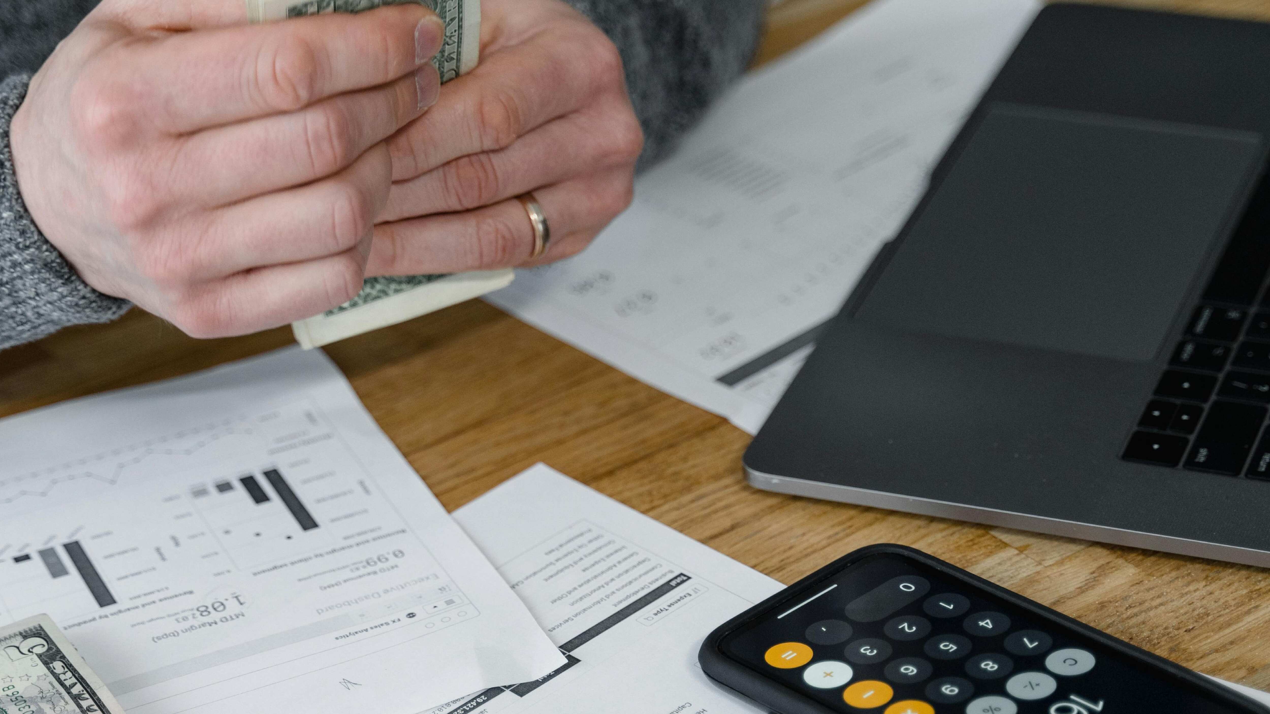 Persona haciendo cuentas y con dólares en la mano