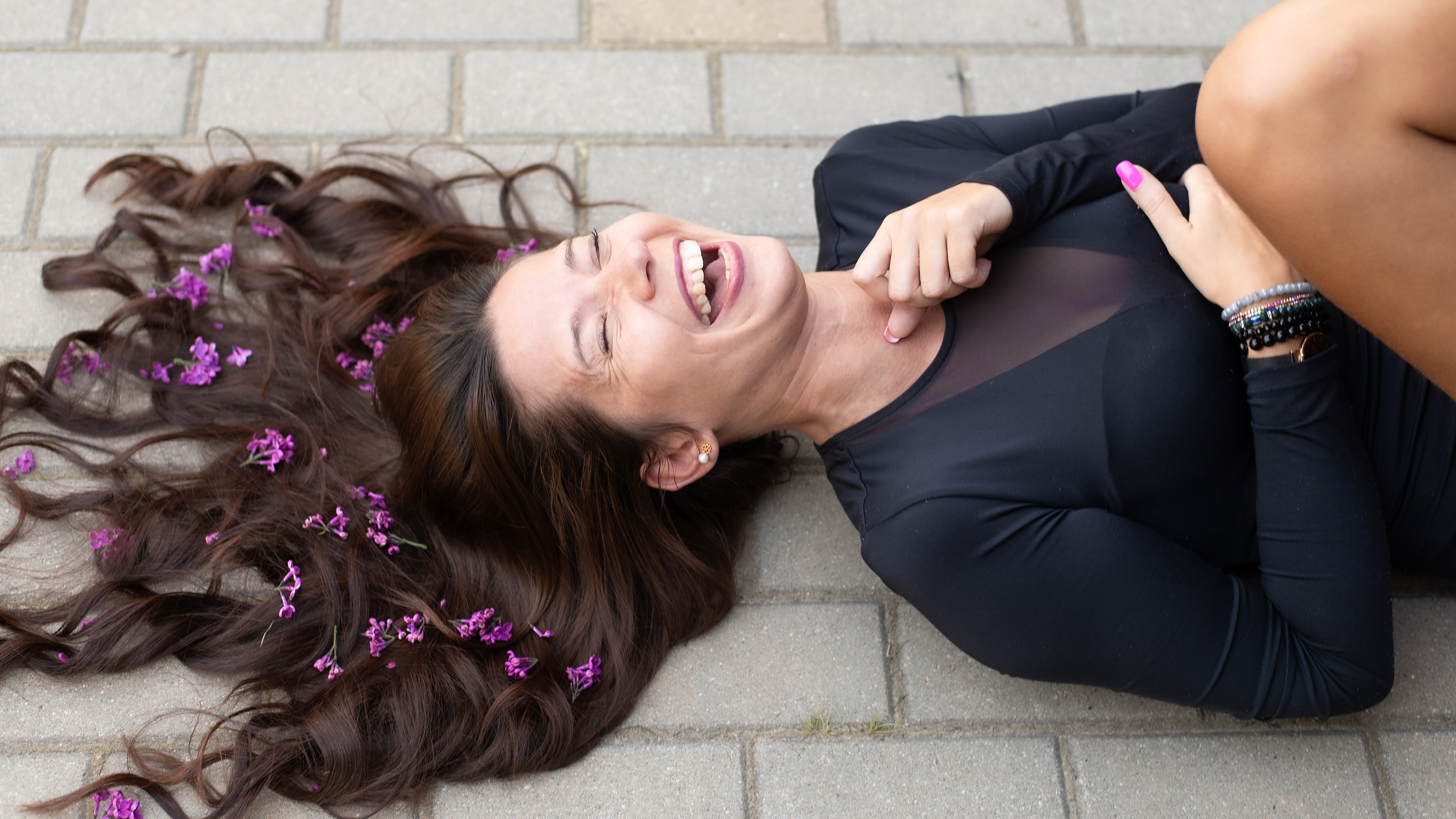 Vista desde arriba de una mujer con flores lilas en el cabello mientras ríe