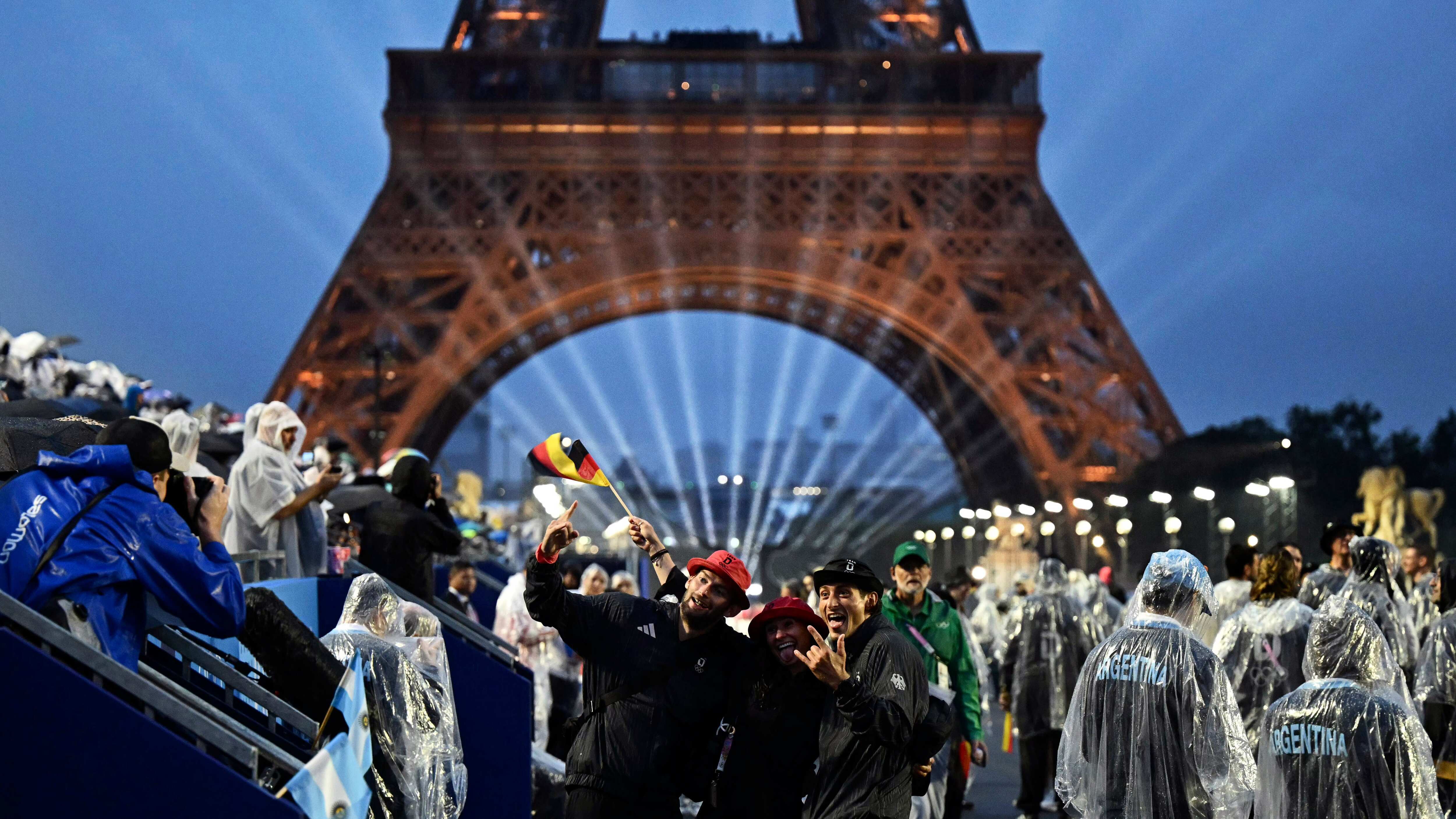 Miembros de la delegación belga llegan al Trocadero mientras la Torre Eiffel y los anillos olímpicos se iluminan durante la ceremonia de apertura de los Juegos Olímpicos de Verano de 2024