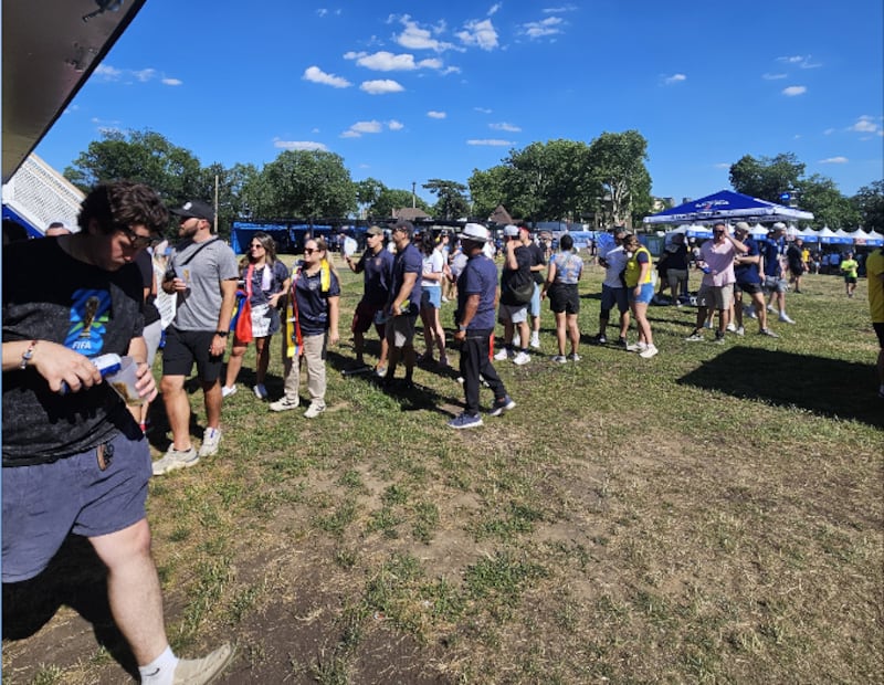 Los aficionados hacen fila en el Fun Fest para comprar alimentos y bebidas bajo un cielo azul y mucho sol.