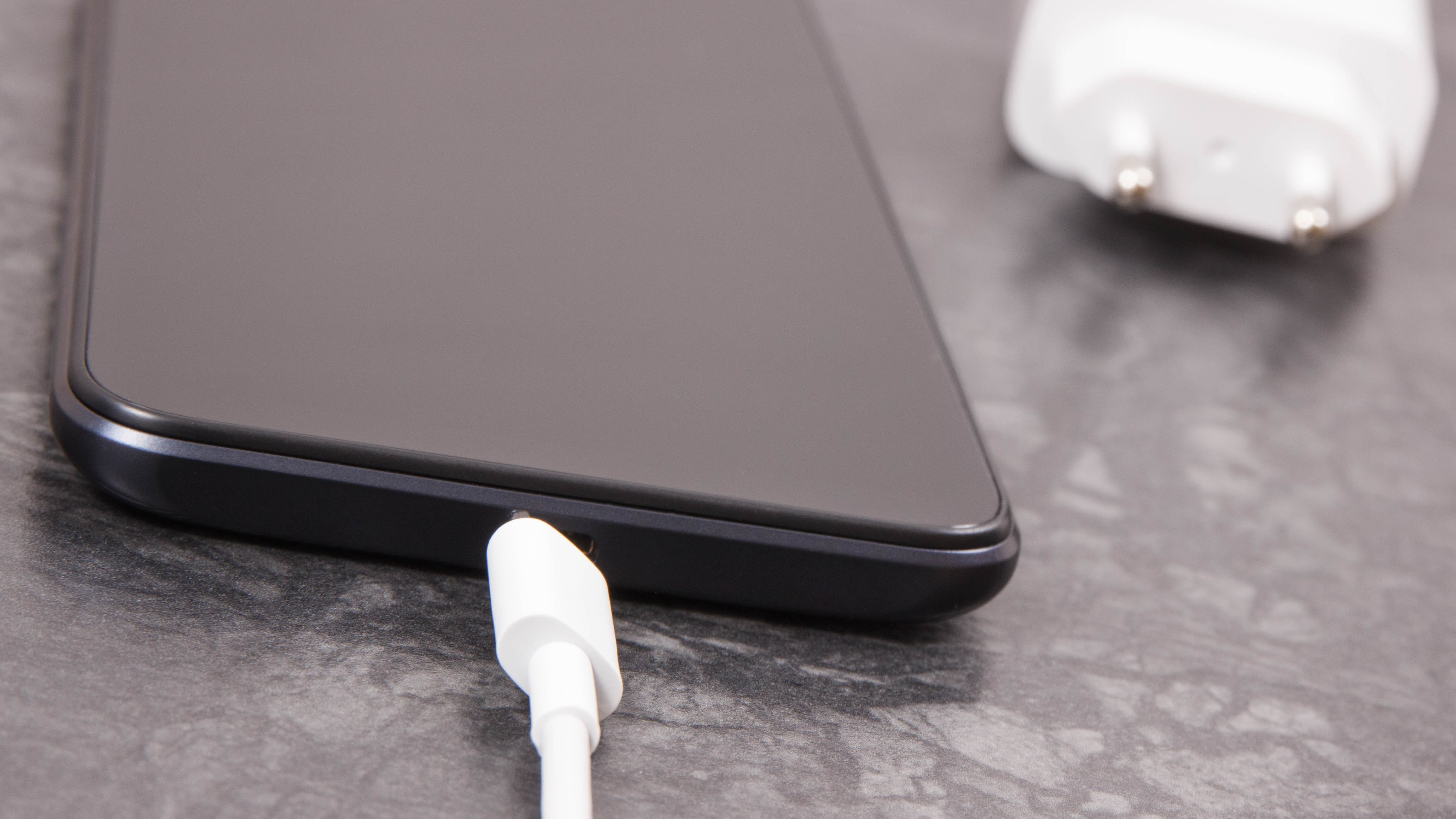 Smartphone negro y cable de cargador desconectado. Carga telefónica